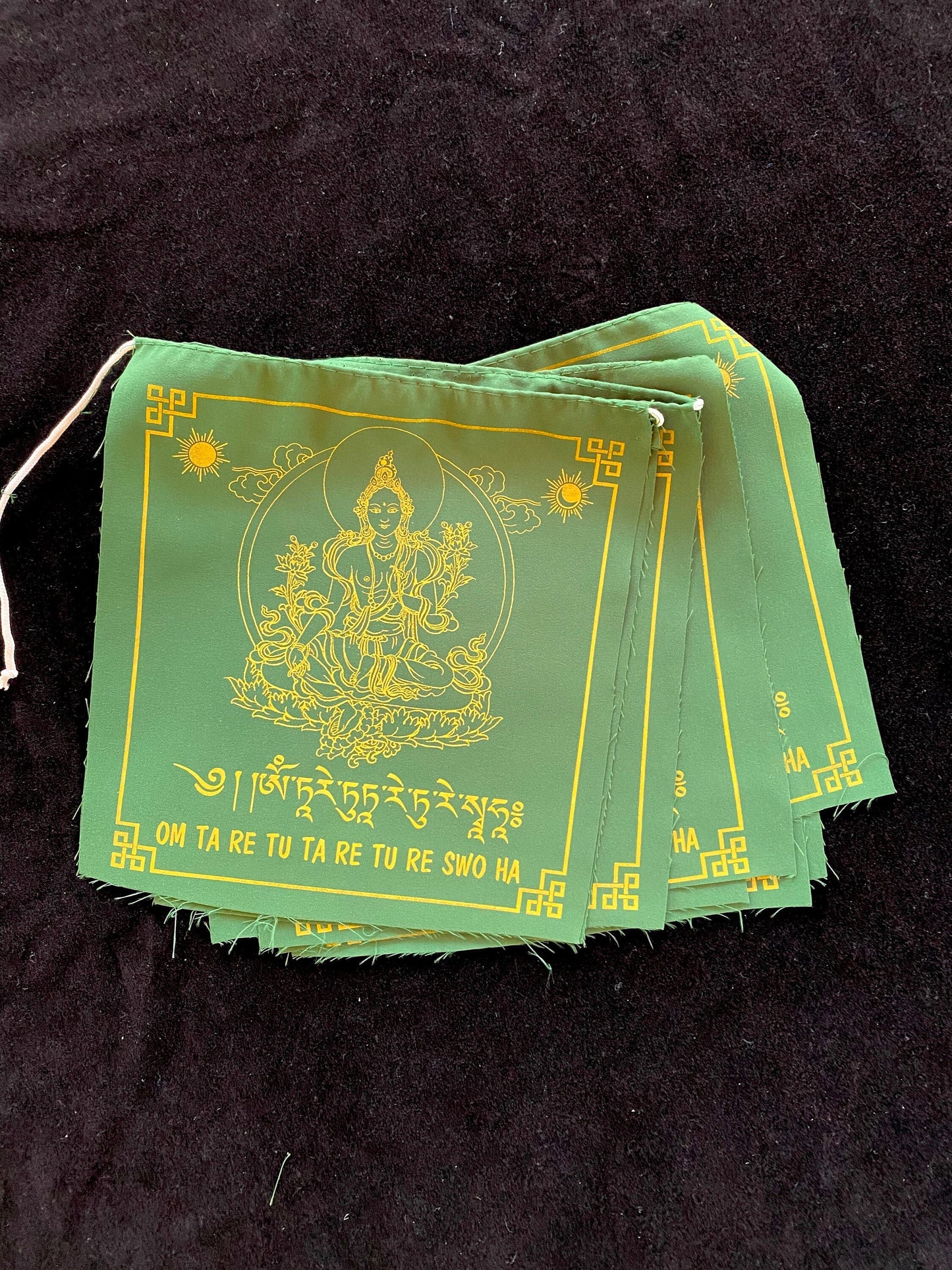 High-quality Tibetan prayer flags: Close-up of 4 Green Tara flag from a set of 10, 8x8 inches each, colored green, imprinted with her image in yellow ink.