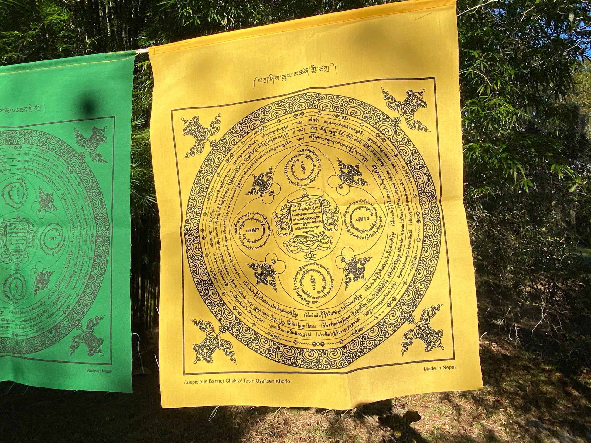 A stunning close-up of a yellow flag from our 25-flag Tashi Gyaltsen or Auspicious Victory Banner Mandala set, beautifully displayed outdoors.