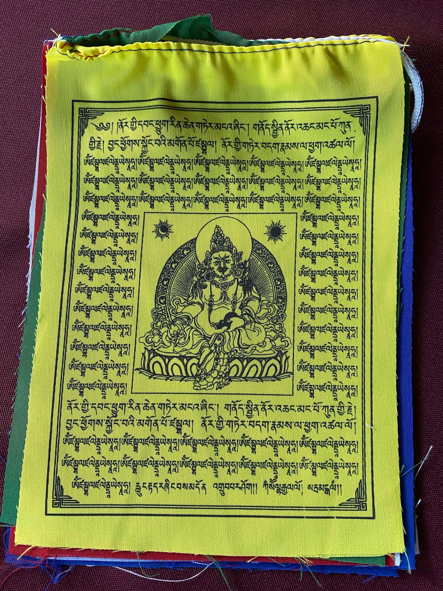 a single yellow flag 6 inch by 7.5 inch Dzambhala wealth deity prayer flags from a  five colored set on a medium background