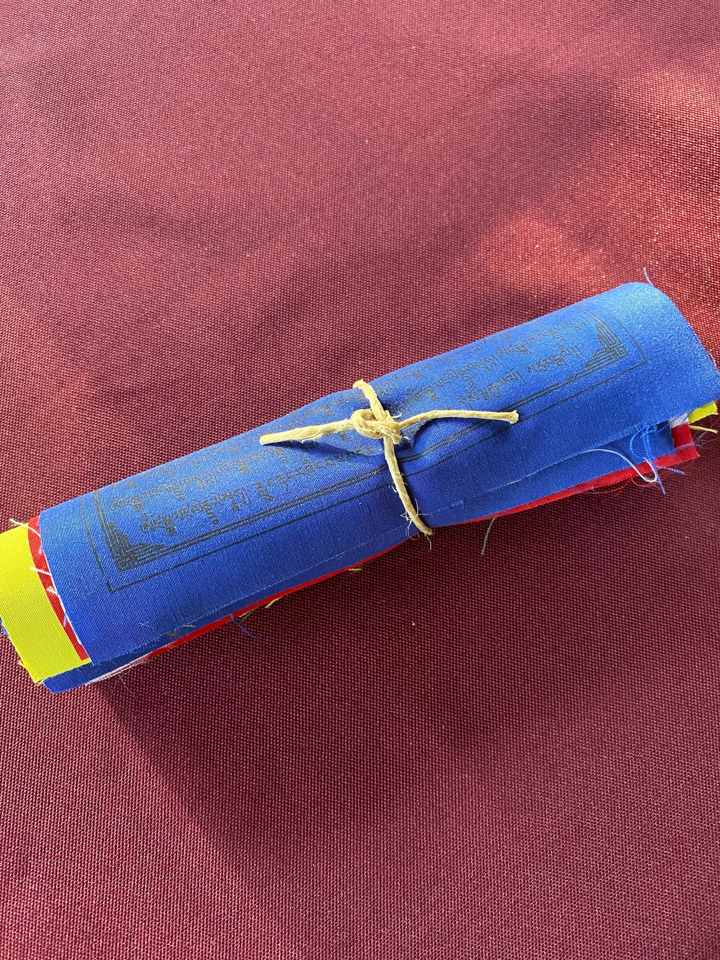 a single flag roll of 6 inch by 7.5 inch Dzambhala wealth deity prayer flags from a  five colored set on a medium background
