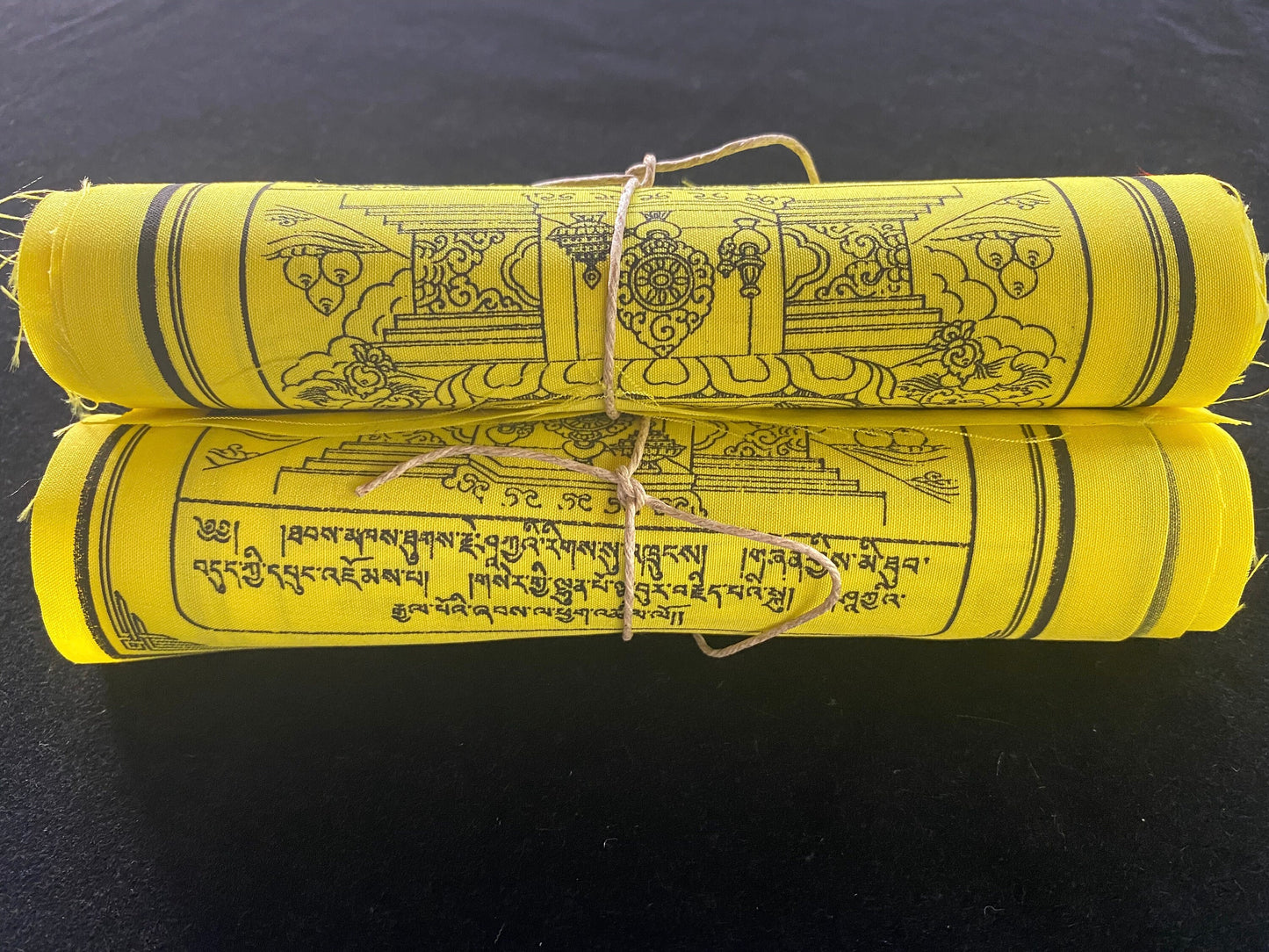 Admire a stunning close-up of 2 rolls of 10 all-yellow Buddha Shakyamuni Prayer flags, each 6&quot;x7.5&quot;, arranged on a black background.