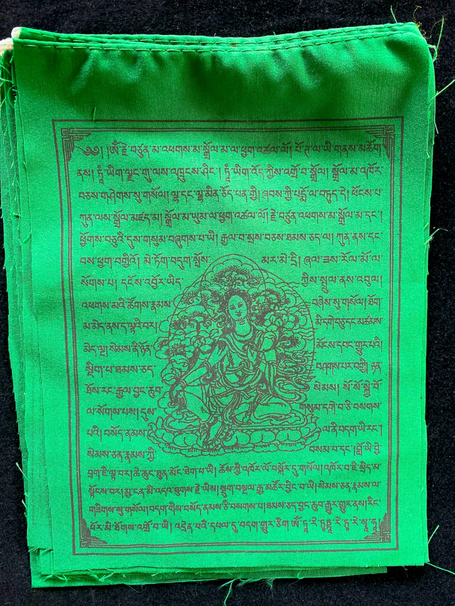 A Green Tara flag from 10-flag strand of high-quality Tibetan prayer flags. Measuring 6x7.5 inches, imprinted with black ink, ideal for indoor/outdoor use.