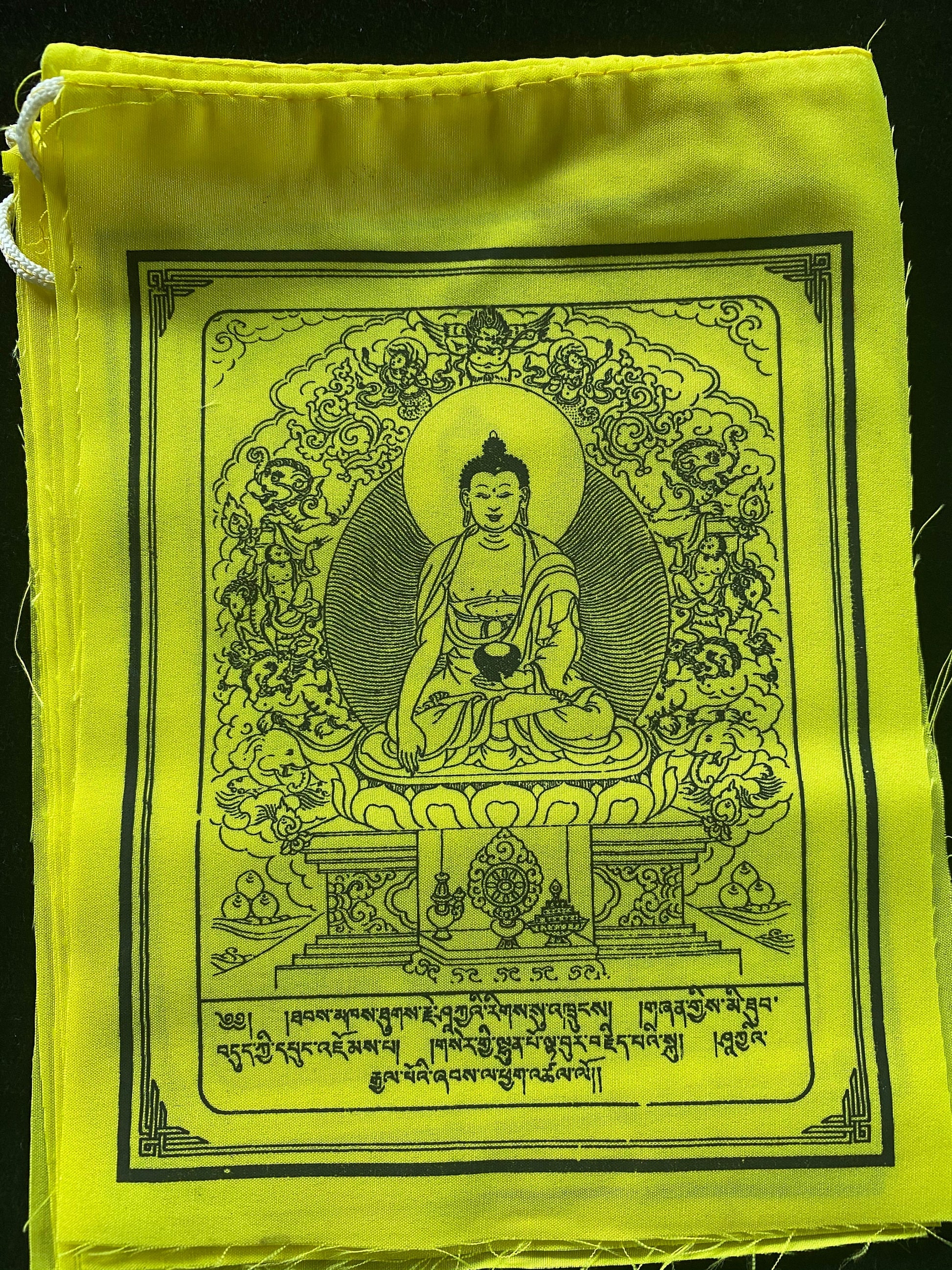 Enjoy a captivating close-up of one of 10 all-yellow Buddha Shakyamuni Prayer flags, each 6&quot;x7.5&quot;, arranged on a black background
