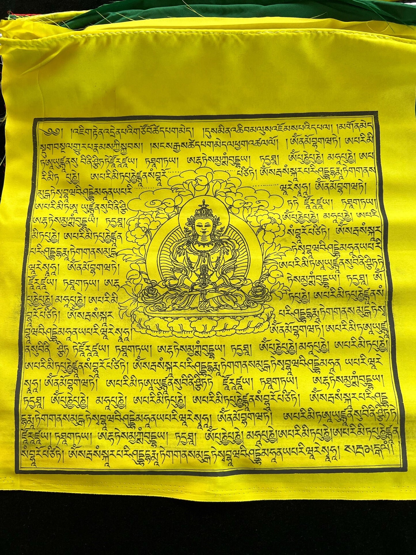 Close-up of yellow Amitayus flag with central deity image and Tibetan prayers, from set of 25 flags, promoting stability and longevity