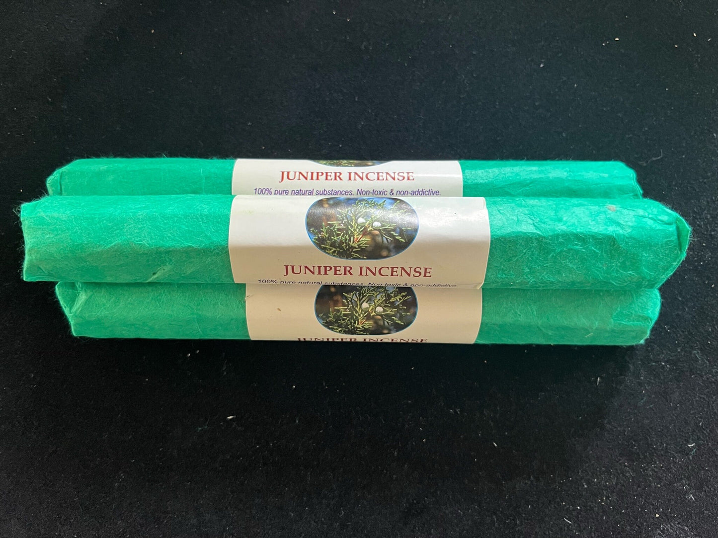 Rolls of Himalayan Arts Juniper Incense on a table. The incense is wrapped in green paper.