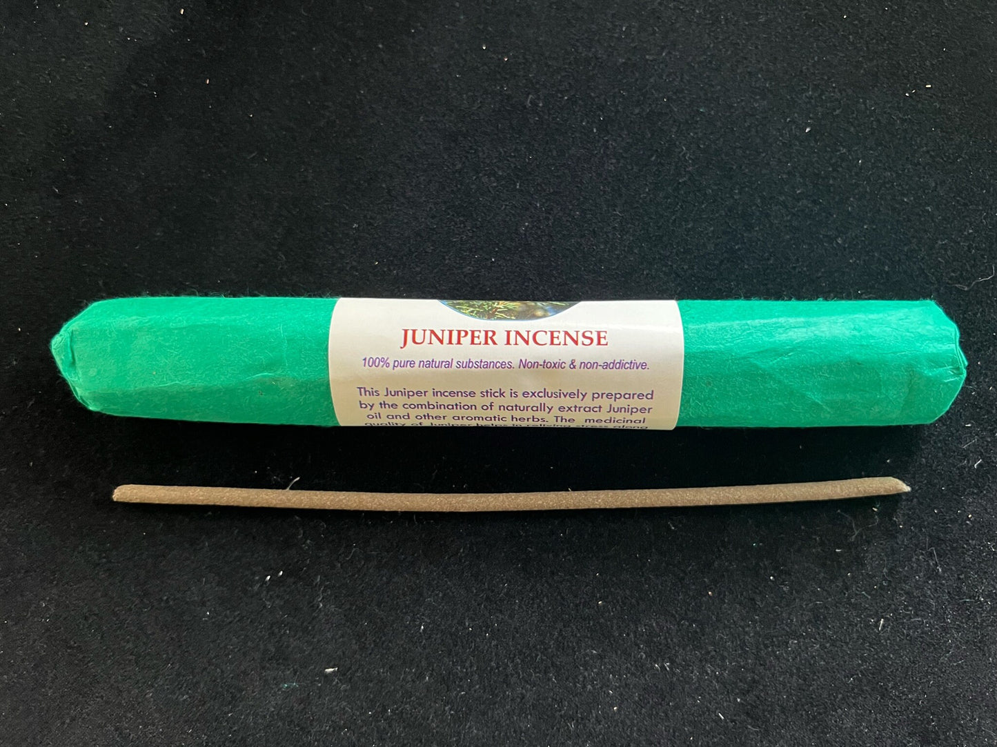 Roll of Himalayan Arts Juniper Incense on a table. The incense is wrapped in green paper.  A single stick is also displayed to show a light green tinted incense.