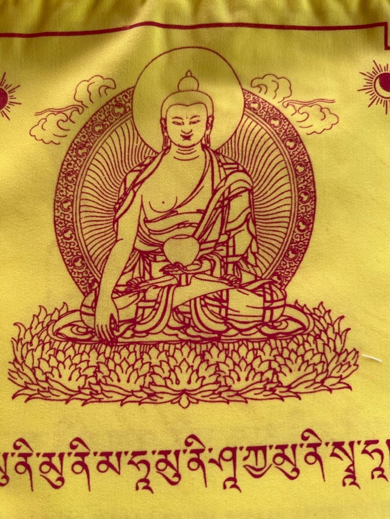 a tight close up of a beautiful all yellow 8x8 inch flag of Buddha Shakyamuni printed in red on a black background.